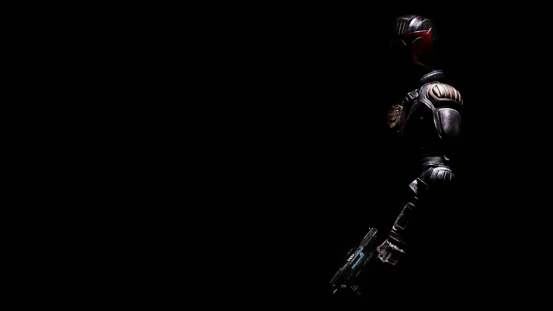 HD PC desktop wallpaper of Judge Dredd from the movie, standing in shadow on a black background with red visor and firearm visible at the right side.