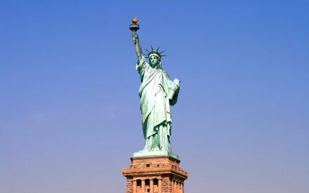 A vibrant HD desktop wallpaper featuring the iconic Statue of Liberty against a clear blue sky, showcasing this remarkable man-made symbol of freedom and democracy.