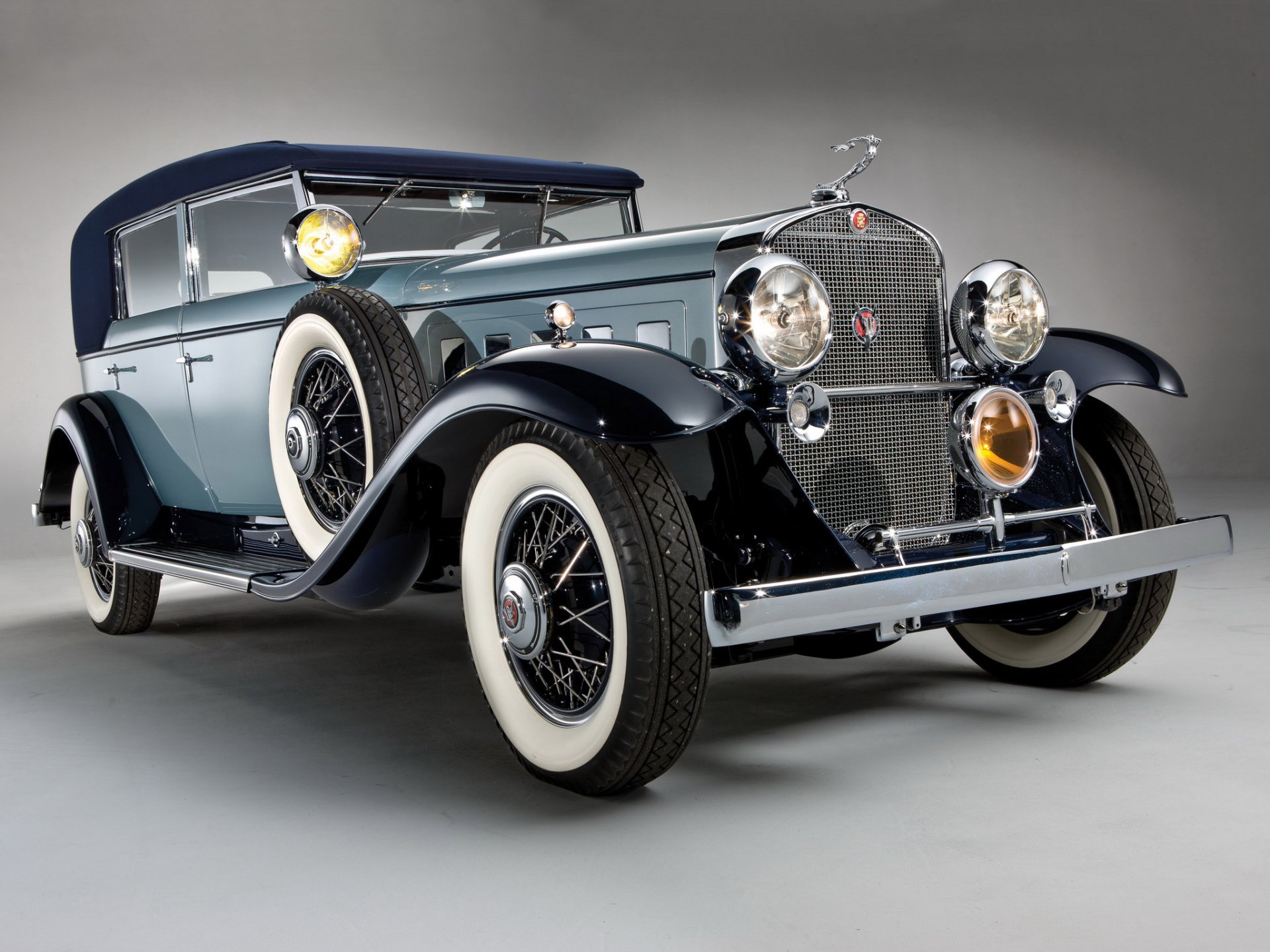 HD PC desktop wallpaper of a 1930 Cadillac V-16 vehicle, restored luxury convertible in three-quarter view with chrome grille and whitewall tires on a neutral studio background.