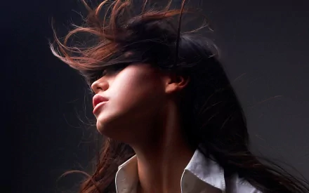 HD PC desktop wallpaper background: woman with flowing hair swept across her face, head tilted back against a dark backdrop.