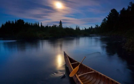HD desktop wallpaper featuring a canoe resting on calm water under a glowing full moon, surrounded by silhouetted trees and a tranquil night sky.