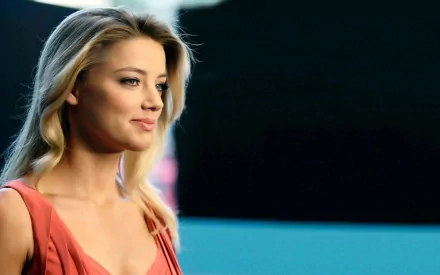 A captivating HD desktop wallpaper featuring celebrity Amber Heard, showcasing her in a striking pose with a soft smile against a blurred background.