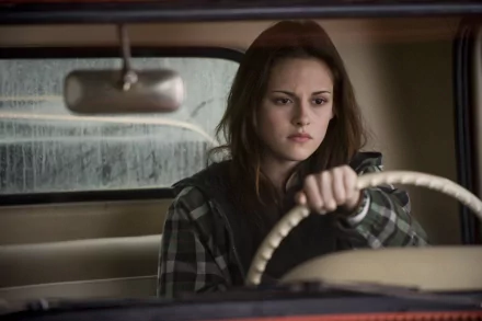 HD desktop wallpaper and background featuring celebrity Kristen Stewart, focused and pensive while driving a car, seen through the windshield with a blurred background.