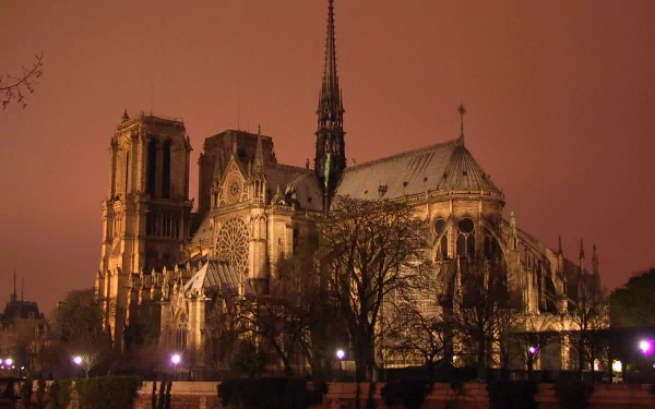 HD desktop wallpaper of Notre-Dame de Paris at dusk, showcasing the iconic religious architecture illuminated against a warm, reddish evening sky.