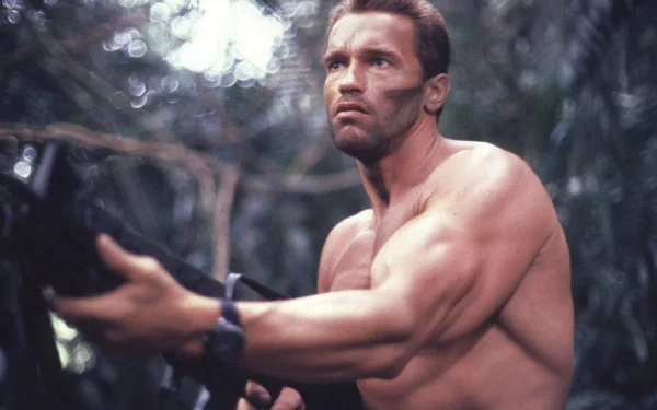 Arnold Schwarzenegger, from the movie Predator, stands in a jungle setting with a determined look and a weapon in hand. HD desktop wallpaper and background.