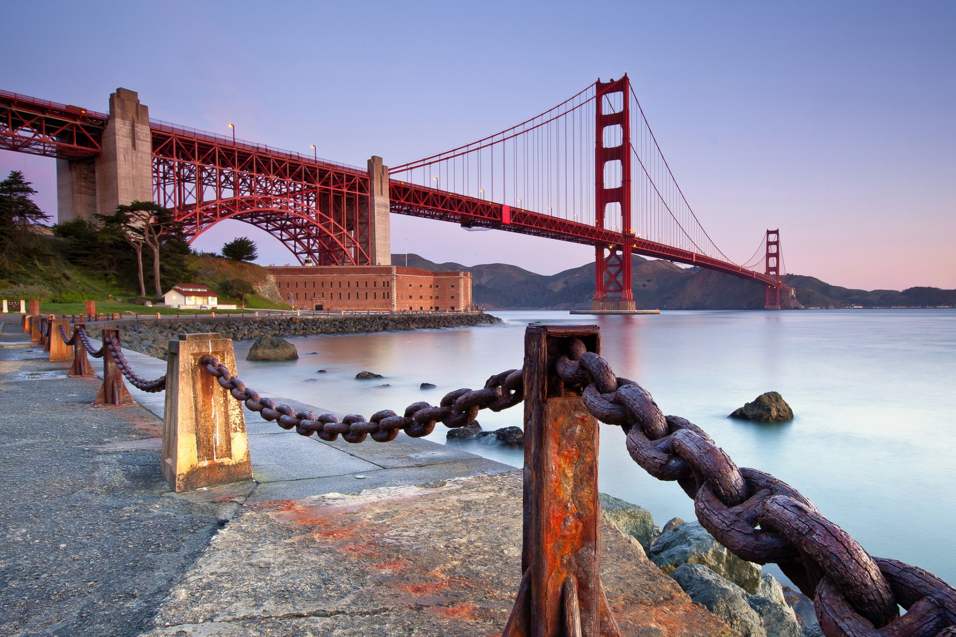 HD desktop wallpaper featuring the iconic man-made Golden Gate Bridge at dusk with a foreground of large chains along the waterfront.