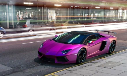 A striking purple Lamborghini Aventador parked on a city street, captured in dynamic motion with blurred lights in the background, serving as an impressive HD desktop wallpaper.