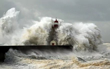 A dramatic scene featuring a lighthouse amid crashing waves, highlighting the power of nature against man-made structures. This HD image serves as an impactful desktop wallpaper.