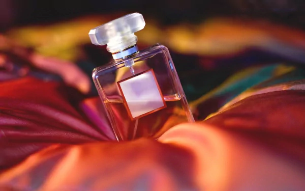 A close-up of an elegant perfume bottle resting on vibrant, colorful fabric, capturing the essence of luxury in this HD desktop wallpaper.