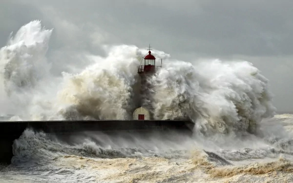 A dramatic scene featuring a lighthouse amid crashing waves, highlighting the power of nature against man-made structures. This HD image serves as an impactful desktop wallpaper.