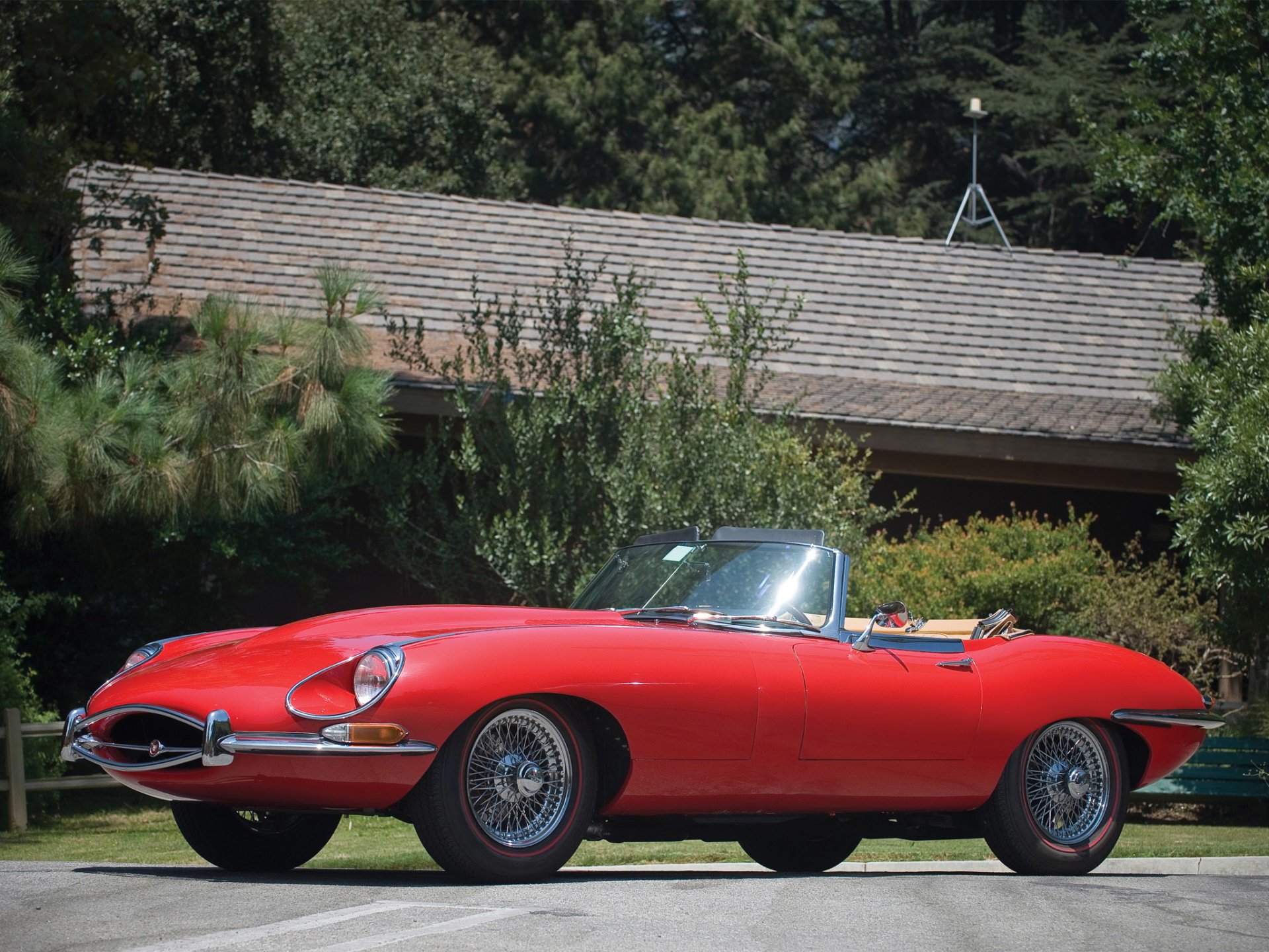 Red Jaguar E-Type vehicle convertible parked on a lawn in front of a house; crisp HD PC desktop wallpaper background showcasing classic car lines.
