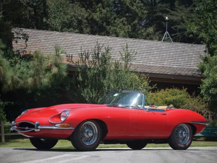 Red Jaguar E-Type vehicle convertible parked on a lawn in front of a house; crisp HD PC desktop wallpaper background showcasing classic car lines.