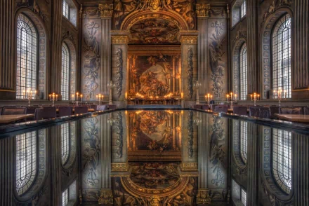 Ornate hall with high arched windows and intricate wall designs, featuring a grand painting at the end and a reflective surface in the center, captured as an HD desktop wallpaper and background.