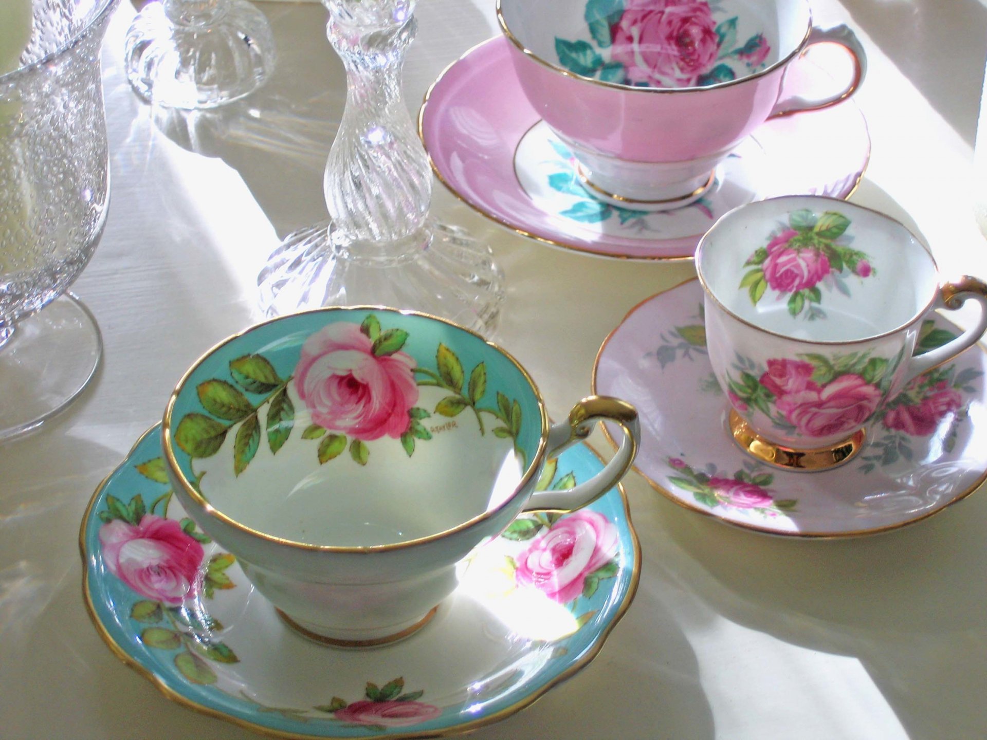 HD still life PC desktop wallpaper featuring elegant porcelain teacups and saucers adorned with pink rose patterns and sparkling glassware on a sunlit table.