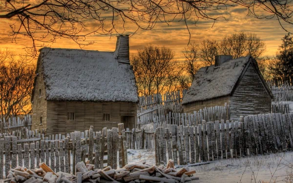HD PC desktop wallpaper featuring a man-made rustic cabin with snow-covered roofs, surrounded by a wooden fence and leafless trees under a golden sunset sky.