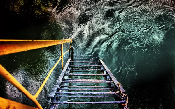 A 4K Ultra HD desktop wallpaper featuring a man-made metal staircase descending into swirling water, captured from above with vibrant colors and detailed textures.