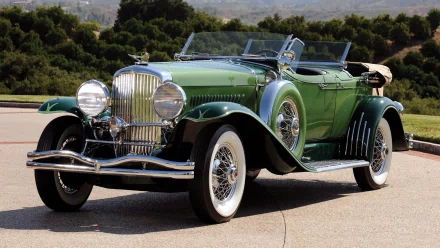 Green Duesenberg Model J Dual Cowl Phaeton vintage vehicle showcased in a high-definition desktop wallpaper background.