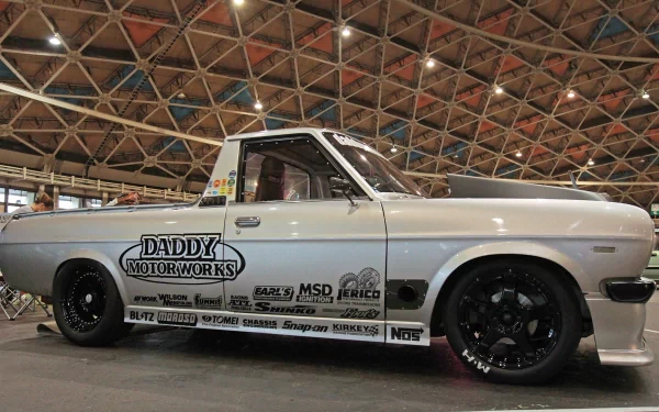 HD desktop wallpaper featuring a classic Datsun vehicle with racing decals, displayed indoors under a geometric glass ceiling.