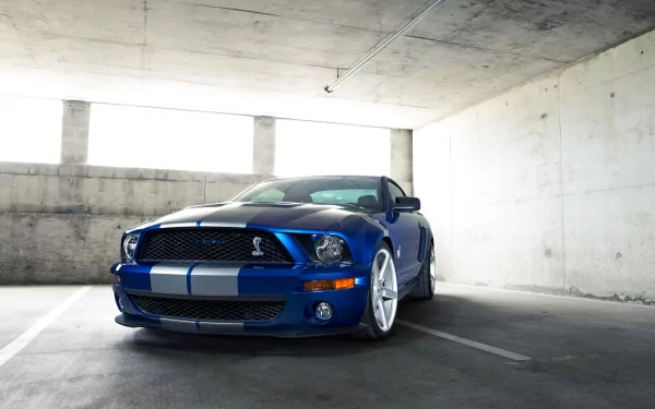 HD PC desktop wallpaper featuring a blue Ford Mustang Shelby GT500 parked in a concrete garage, showcasing its sleek design and racing stripes.