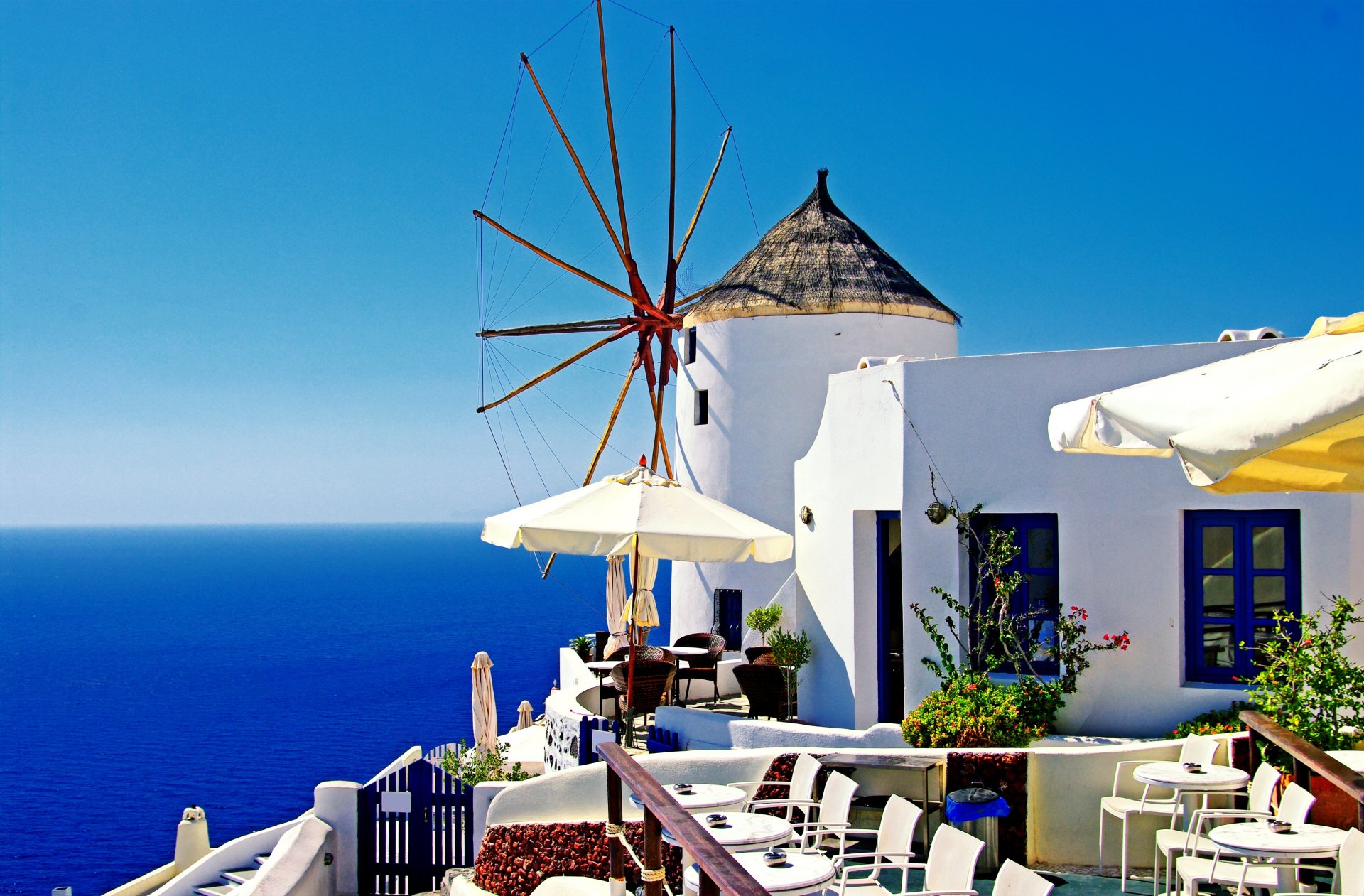 A stunning view of a traditional windmill in Santorini, Greece, overlooking the deep blue sea. This HD image captures the beauty of the island's architecture and landscape.