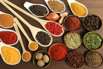 A vibrant array of herbs and spices arranged in bowls and spoons, creating a rich, colorful display that enhances any culinary-themed HD desktop wallpaper or background.
