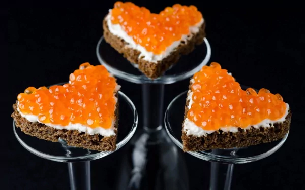 HD desktop wallpaper featuring heart-shaped appetizers topped with vibrant orange caviar on a dark background, highlighting food and caviar themes.