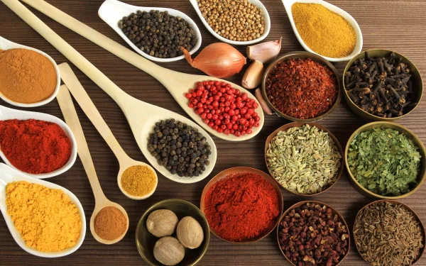 A vibrant array of herbs and spices arranged in bowls and spoons, creating a rich, colorful display that enhances any culinary-themed HD desktop wallpaper or background.