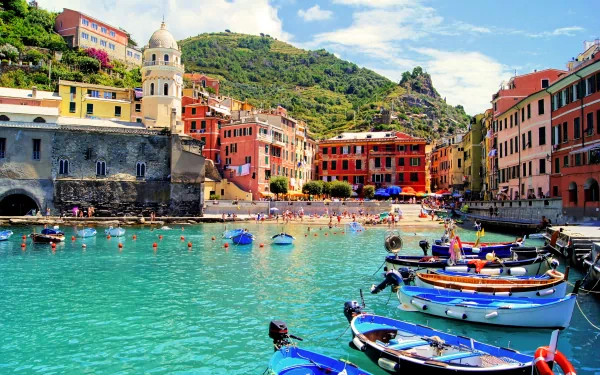 A vibrant view of Vernazza in Cinque Terre, Italy, showcasing colorful buildings, clear turquoise waters, and boats in the foreground, capturing the charm of this picturesque village.