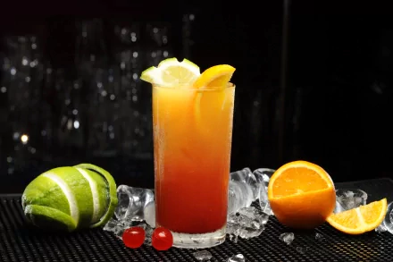 A vibrant cocktail garnished with citrus slices sits atop a bed of ice, accompanied by lime and orange halves. This 4K Ultra HD wallpaper captures the essence of refreshing drinks.