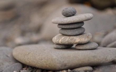 HD desktop wallpaper of a balanced stack of smooth stones set against a soft-focus natural background.