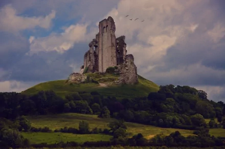 A breathtaking 4K Ultra HD image of a majestic ruin atop a hill, surrounded by lush greenery and dramatic clouds, offering a glimpse into man-made history against a natural backdrop.