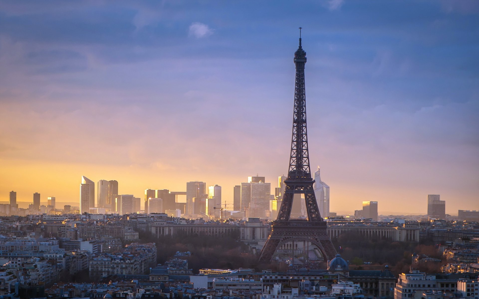 A stunning HD wallpaper showcasing the Eiffel Tower against the Paris skyline at sunset, highlighting the blend of historic architecture and modern cityscape.