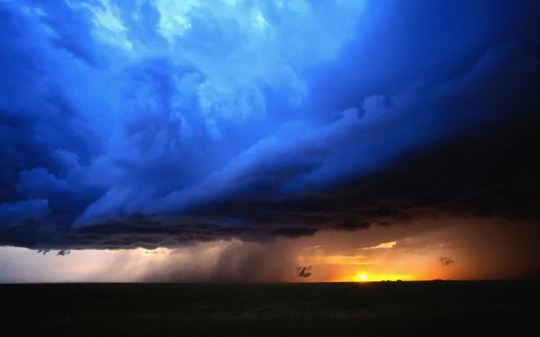 HD desktop wallpaper featuring a dramatic storm rolling over a dark landscape with a vibrant orange sunset glowing on the horizon.