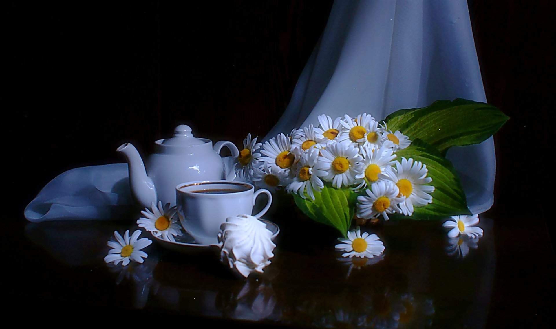 HD PC desktop wallpaper showing a white teapot, teacup, and a bouquet of fresh chamomile flowers on a dark reflective surface with a soft blue draped background.