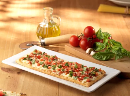 Delicious pizza topped with fresh tomatoes, basil, and a drizzle of olive oil, displayed on a white platter with vibrant ingredients, making a charming HD desktop wallpaper.