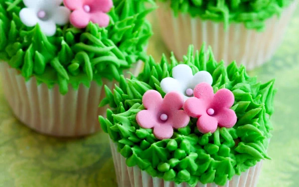 Vibrant green grass-themed cupcakes adorned with pink and white flower decorations, showcased in a stunning 4K Ultra HD desktop wallpaper.