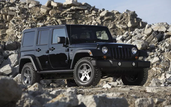 A black Jeep Wrangler parked on rocky terrain, highlighting its rugged design. This HD wallpaper showcases the vehicle against a natural backdrop.
