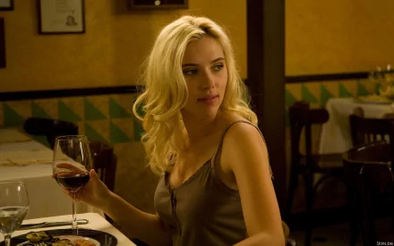 Scarlett Johansson in a restaurant setting, elegantly holding a glass of red wine. This captivating HD wallpaper captures a moment of sophistication and charm.