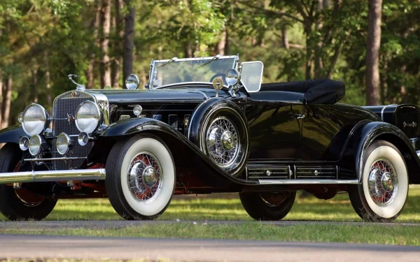 Black vintage Cadillac V16 convertible parked on a tree-lined road; high-resolution 2K Quad HD PC desktop wallpaper/background.