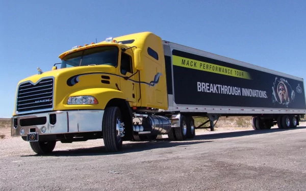 HD desktop wallpaper featuring a yellow Mack Trucks vehicle with a trailer displaying Breakthrough Innovation in a clear, sunny outdoor setting.