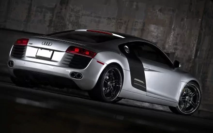 A sleek Audi R8 parked in a dimly lit space, showcasing its distinctive rear design and modern curves, serves as a captivating HD PC desktop wallpaper and background.