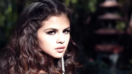 HD desktop wallpaper of Selena Gomez with a music theme, featuring her looking directly into the camera with a natural background.