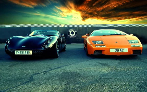 HD PC desktop wallpaper featuring two vehicles: a black sports car and an orange Lamborghini Diablo under a dramatic sunset sky.