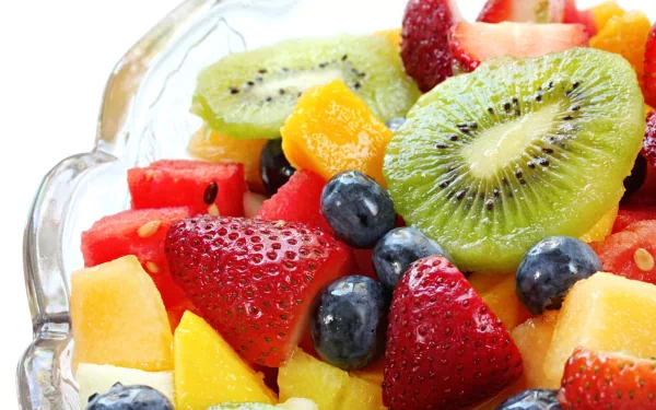 A vibrant bowl of mixed fruit featuring strawberries, kiwi, blueberries, watermelon, and cantaloupe. This colorful image serves as a refreshing HD desktop wallpaper and background.