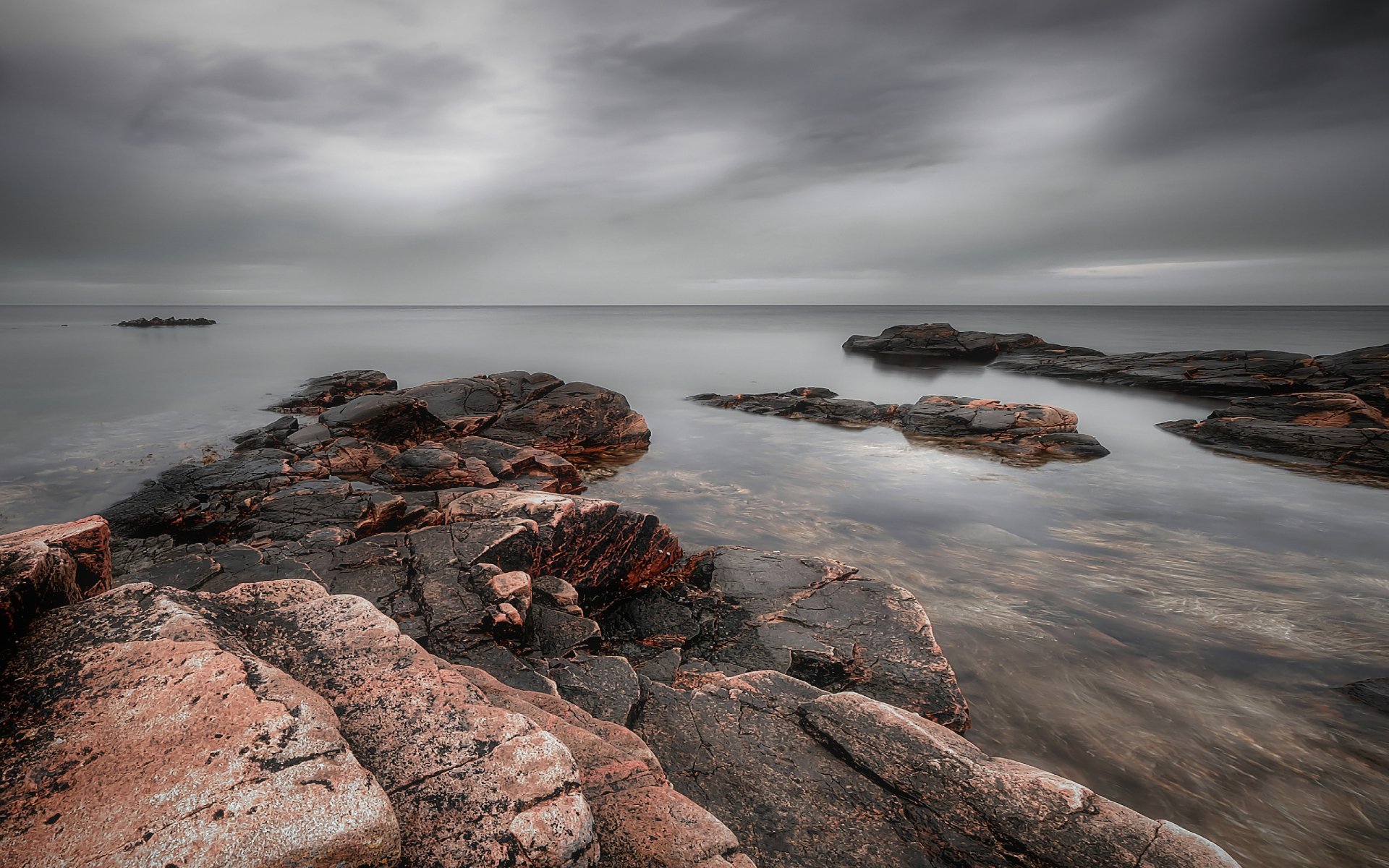 HD PC desktop wallpaper of a serene ocean scene featuring rocky shores under a cloudy sky, showcasing the calming beauty of nature and the sea.