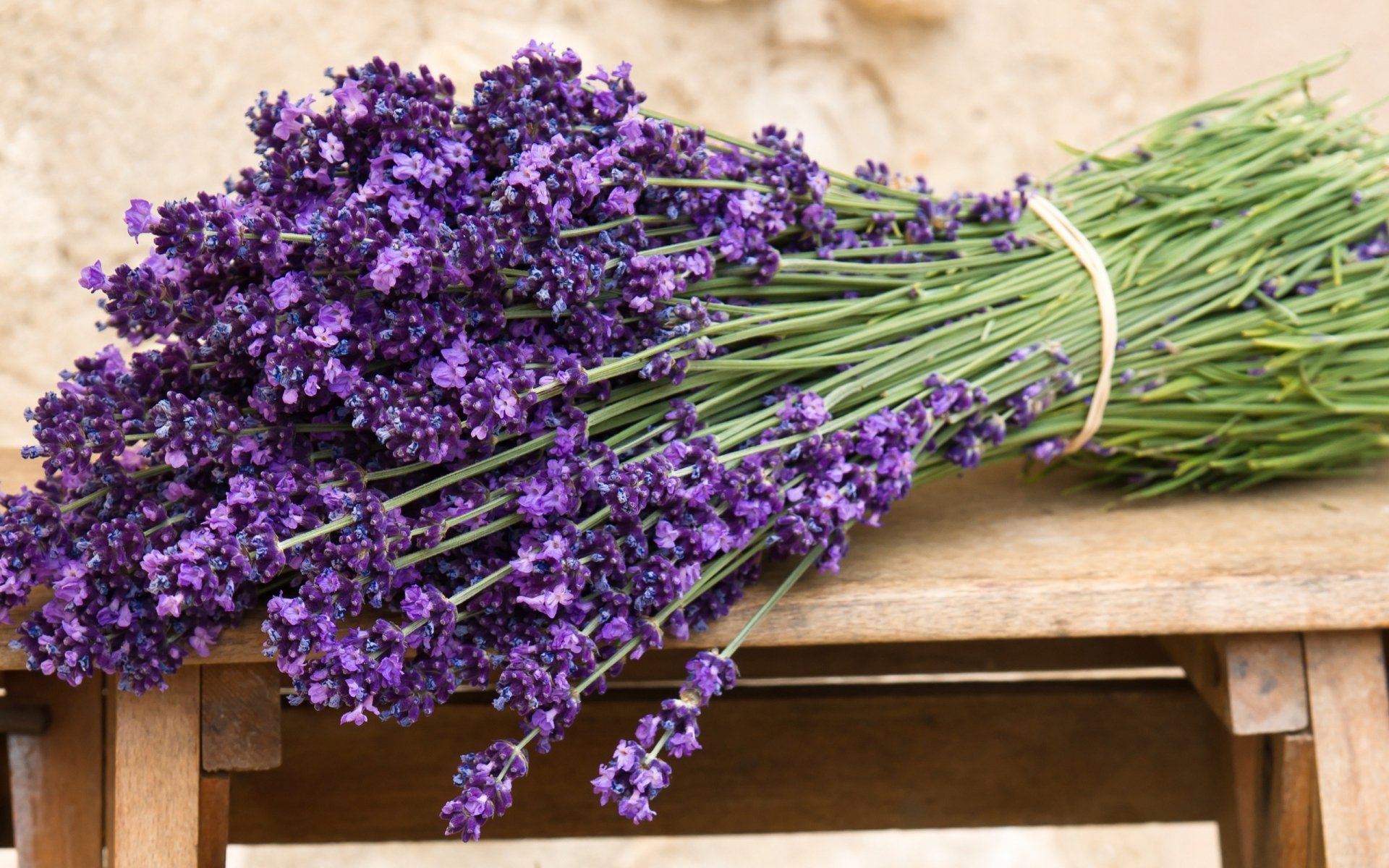 HD desktop wallpaper featuring a vibrant bundle of freshly picked lavender flowers resting on a wooden surface, showcasing the beauty of nature.
