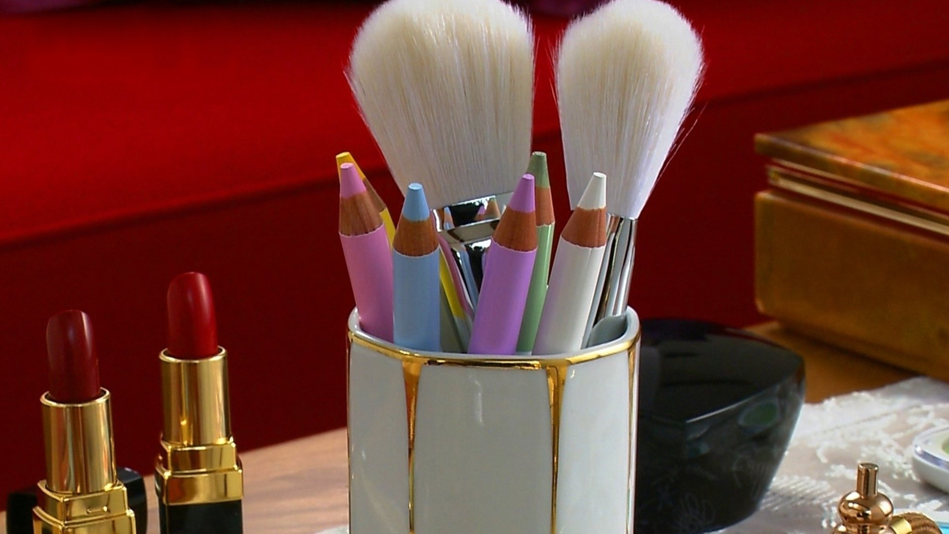 A stylish arrangement of makeup brushes and colorful pencils in a chic container, set against a vibrant background. This HD photograph serves as a stunning desktop wallpaper and background.