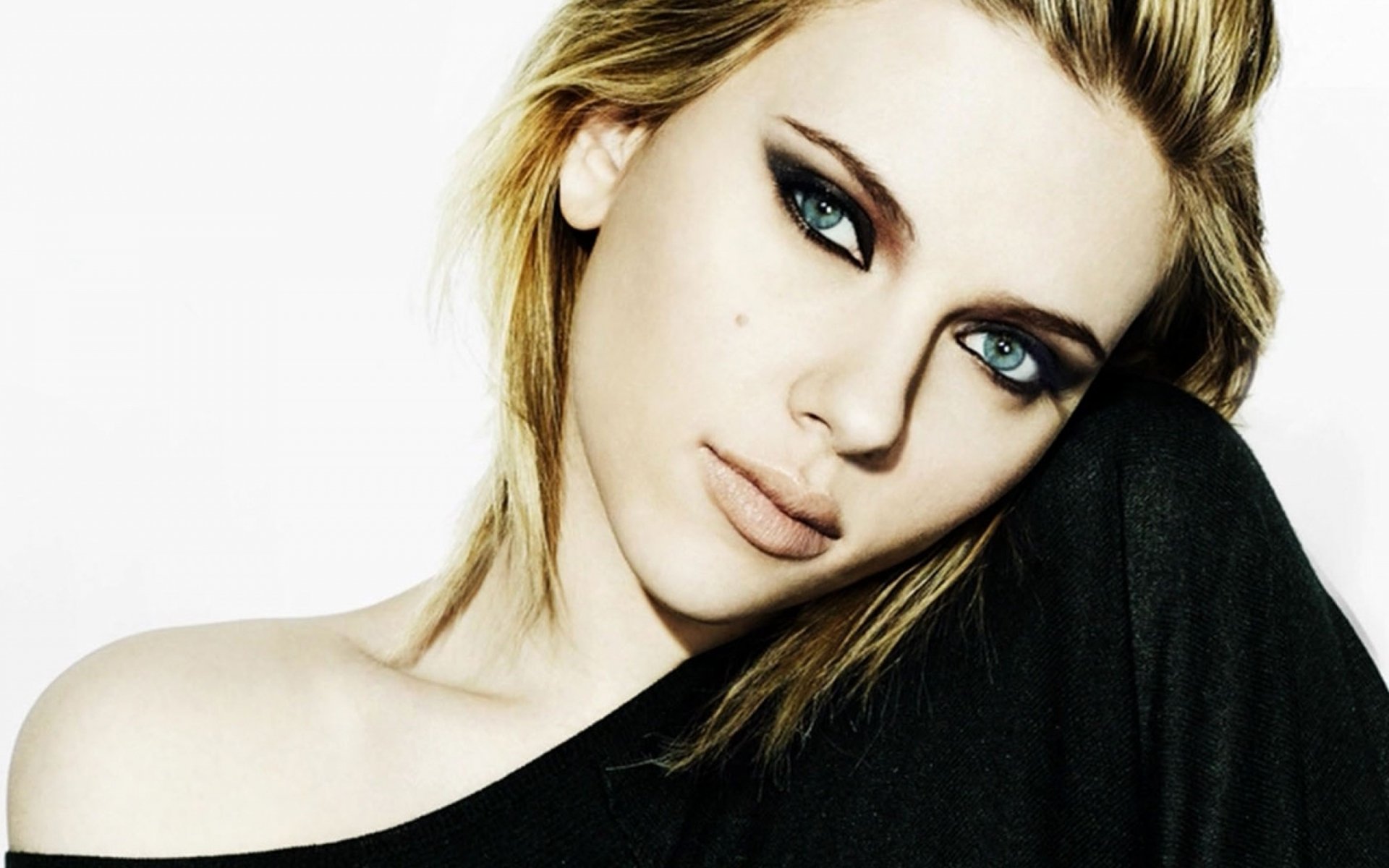Blonde celebrity Scarlett Johansson in an HD desktop wallpaper, looking directly at the camera with a neutral expression, wearing a black top against a simple white background.