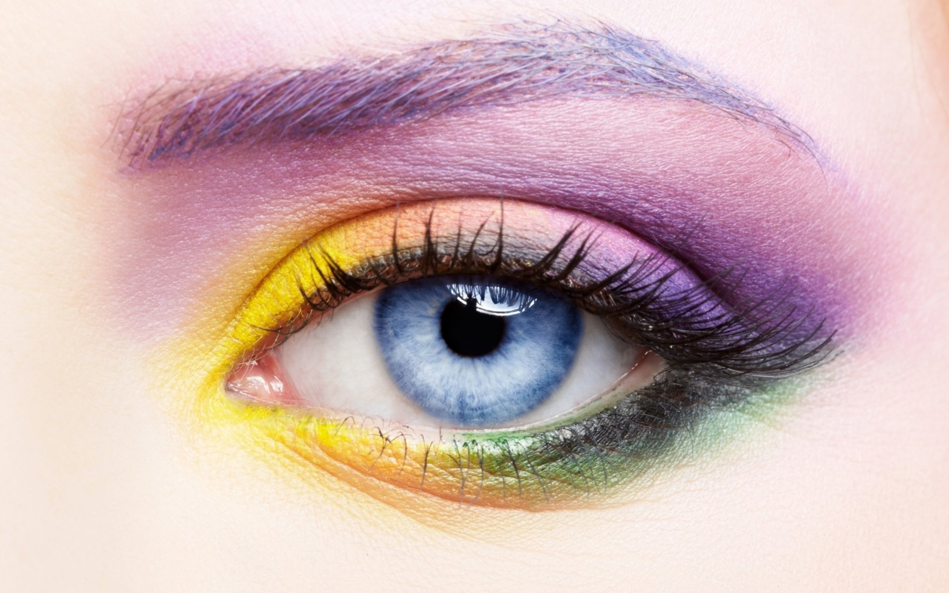 A close-up of a woman's eye featuring vibrant, artistic makeup in blue, purple, and yellow hues, set against a smooth background, making it an engaging HD PC desktop wallpaper.