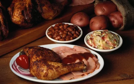 A delicious meal featuring seasoned roasted chicken, sliced ham, baked beans, creamy coleslaw, and fresh potatoes, captured in high-definition for an enticing desktop wallpaper.